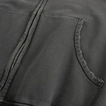Macro detail of the charcoal hoodie: the zip placket and the curved pocket mouth, with the edge deliberately abraded so the raw cotton shows through