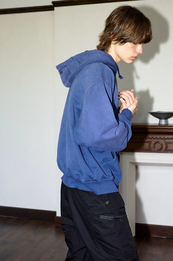 Washed indigo hoodie seen from the side, showing the dropped shoulder and the low sleeve head