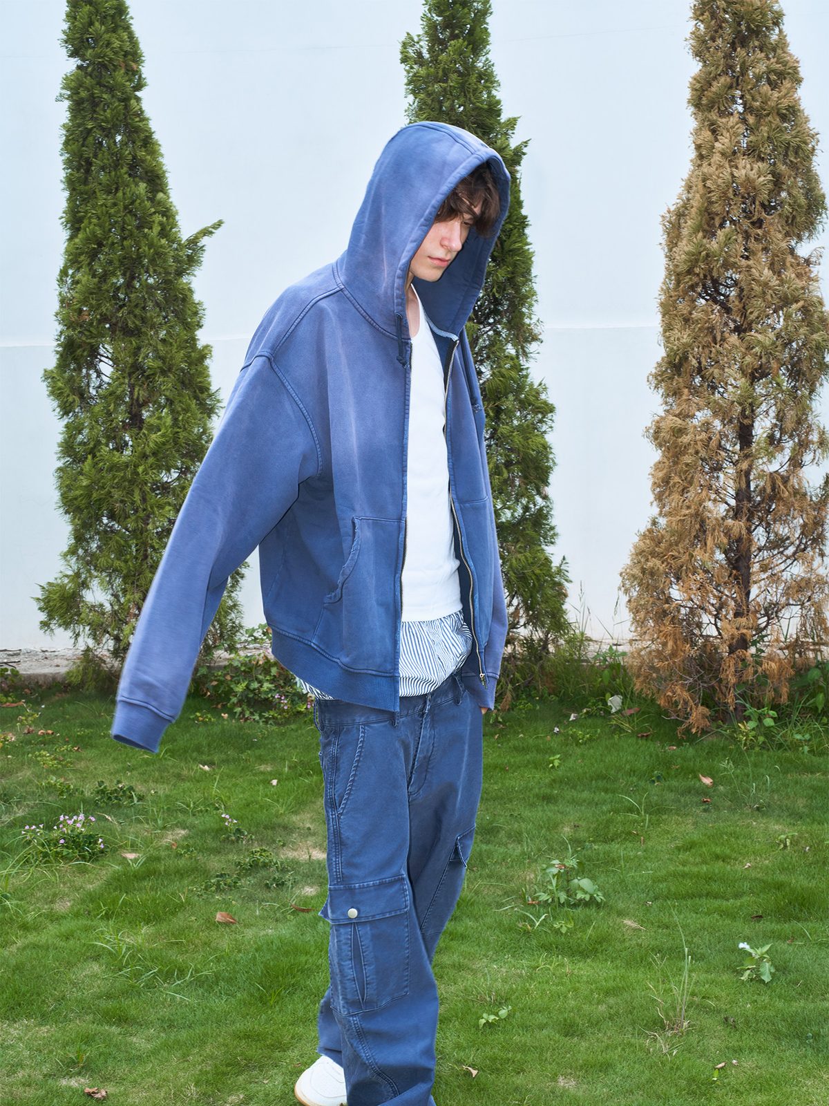 Washed indigo hoodie worn hooded with matching cargo trousers, three-quarter view