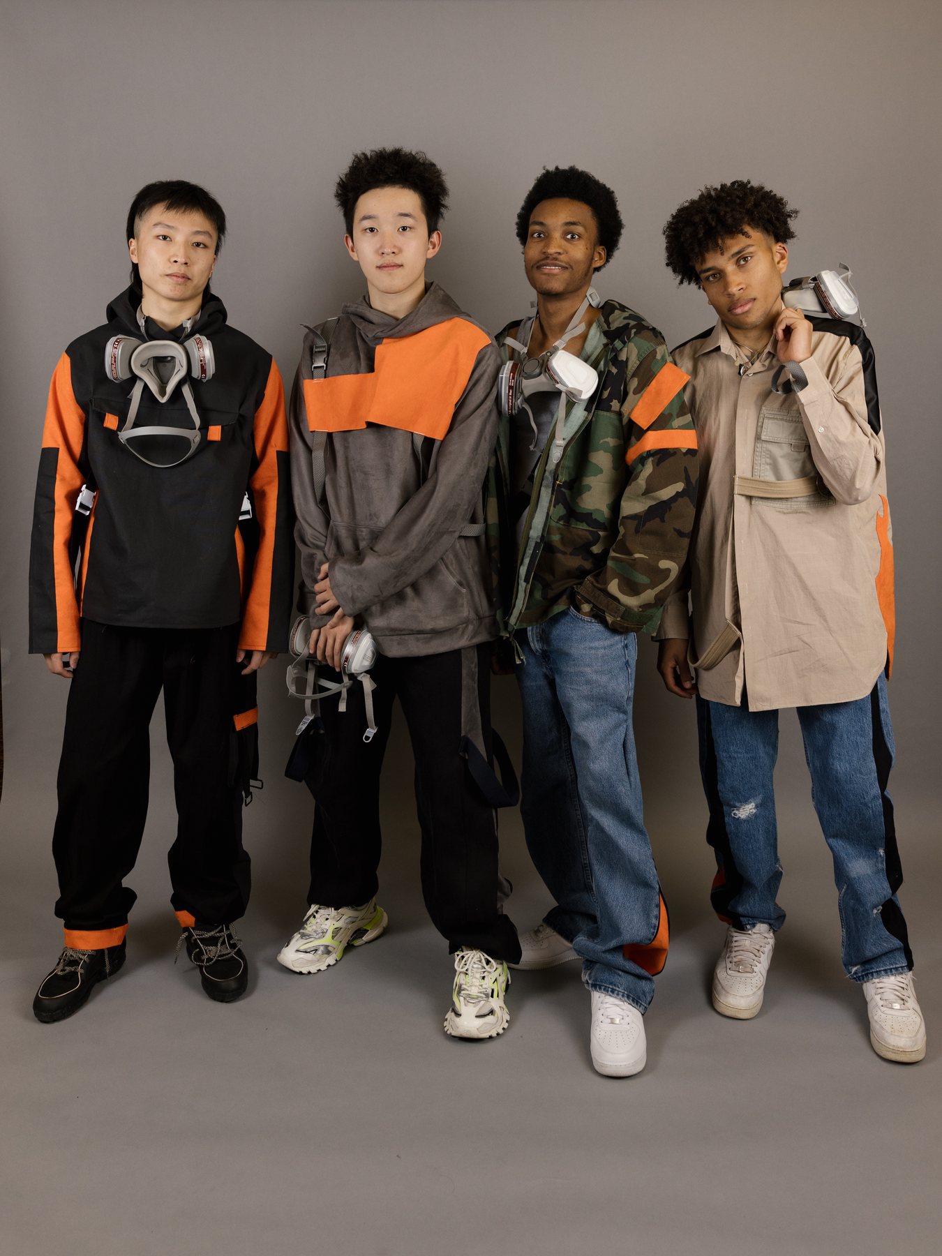 Four models on a plain grey ground, each wearing the same issued respirator a different way