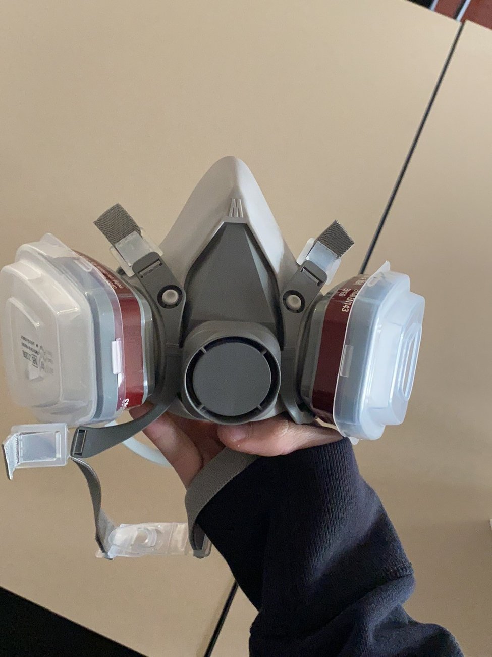 The issued half-mask respirator held up in the fitting room