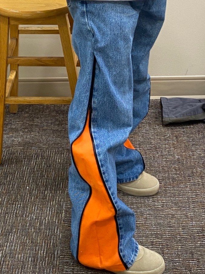 Trouser with the side zip open, the lower leg falling away from a wave-cut orange panel