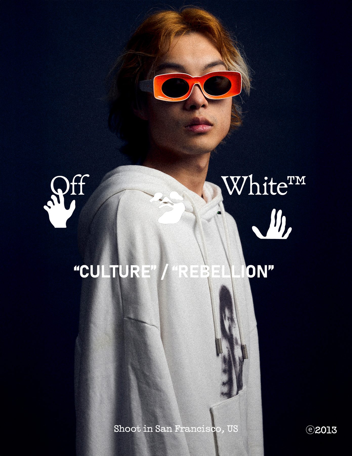Model in orange sunglasses and an off-white hoodie against a dark ground